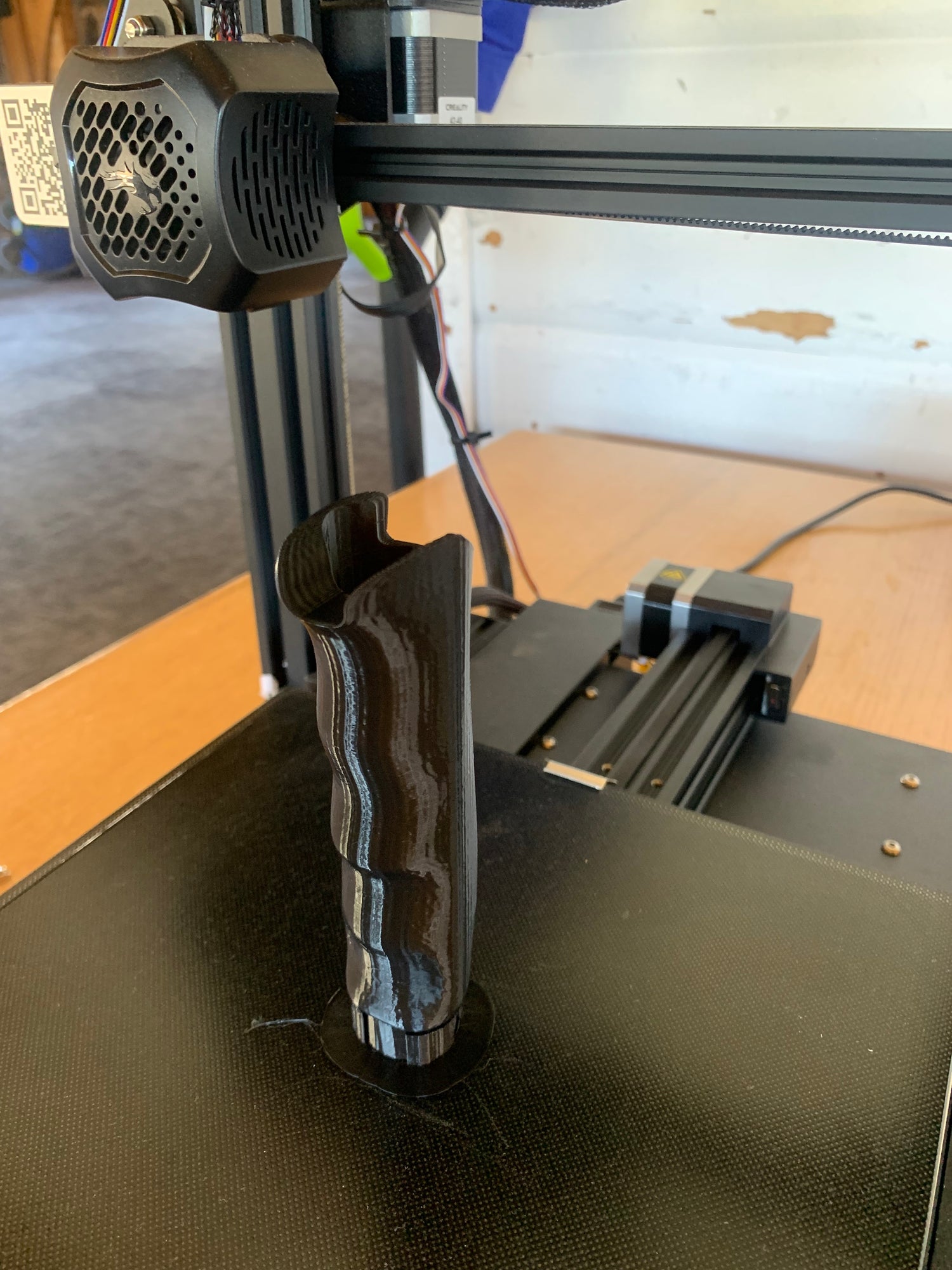 3D-printed prototype of the Pepper Poles handle on a printer bed, featuring an ergonomic grip and an integrated pepper spray compartment for safety on the trail.